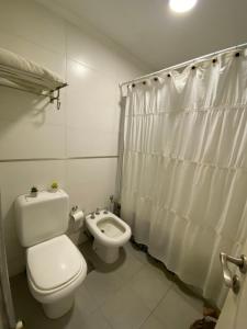 a white bathroom with a toilet and a bidet at Moderno piso con vista al río en zona residencial in San Nicolás de los Arroyos