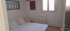 une chambre avec un lit blanc et une fenêtre dans l'établissement Appartement vue mer Aiguebelle, au Lavandou