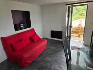 a red couch in a living room with a television at Mas cevennes in Concoules