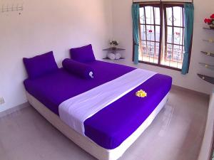 a large purple bed in a room with a window at 24/7 Bed & Breakfast in Jimbaran