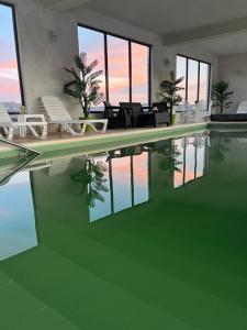 a swimming pool with chairs and a table and water at Hotel Ariana in Tăşnad