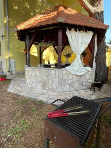 a barbecue grill with a gazebo with a cat standing behind it at Apartments Villa-G Lustica in Tivat