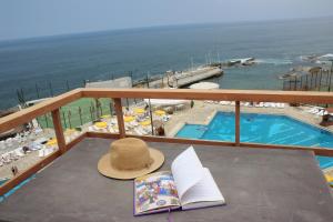 a hat and a book on a balcony with a pool at Cimer SafraMarine Beach Resort in Safra