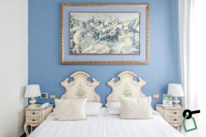 ヴェネツィアにあるHOTIDAY Room Collection - Venezia Santa Luciaの青いベッドルーム(ベッド2台付)が備わります。壁には絵画が飾られています。