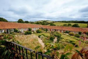 a row of brick buildings with a garden in the foreground at Hayloft Cottage - Rudge Farm Cottages in Bridport