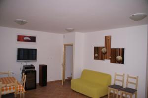 a living room with a yellow couch and a tv at Öregtölgy Vendégház in Csongrád