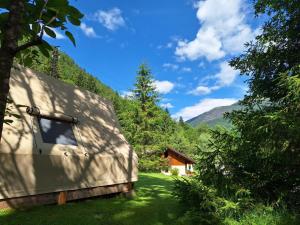 a house in the middle of a field with trees at Presanella Mountain Lodge in Temù