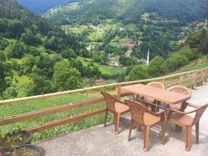 a wooden table and chairs on a balcony with a view at AYDIN HOME Uzungöl in Uzungöl