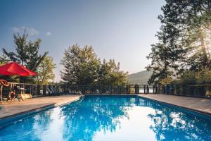 a blue swimming pool with a red umbrella at Lakefront, Mountain View - Resort Loft in Lac-Superieur