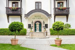 a hotel with two potted trees in front of a building at Hotel Gut Ising in Chieming