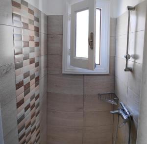 a bathroom with a shower with a window at Katerinas Home in Agios Prokopios