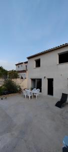 ein weißes Gebäude mit Tischen und Stühlen davor in der Unterkunft Maison de vacances in Saint-Clément-de-Rivière