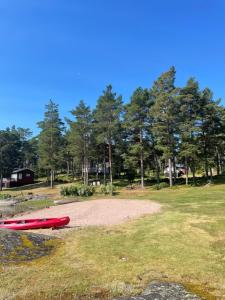 a red kayak sitting on the ground in a field at Pikkumökki Sveastugan in Rövik