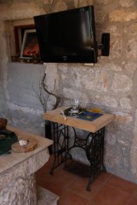a television hanging on a stone wall with a table at Appartement Balthasar - Turm Krk in Sveti Vid-Miholjice