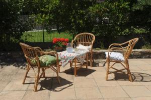 a table with three chairs and a table with flowers on it at Casa Franguella - Uliveto sul mare in Lavagna