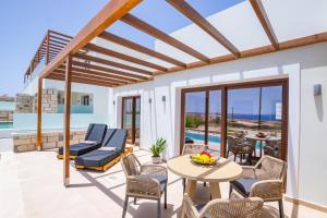 a patio with a table and chairs and a pool at Elite Luxury Villas in Afiartis