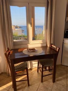 a dining room table with two chairs and a window at Miros apts in Agia Pelagia 50m from the beach in Agia Pelagia