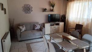 a living room with a couch a table and a tv at Spiti TRIVIZAS in Agrós