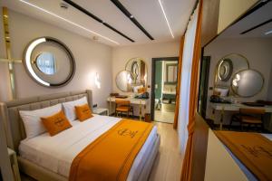 una camera da letto con letto, cuscini arancioni e specchio di Elysian Airport Hotel a Arnavutköy