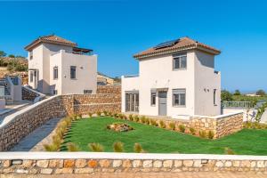 a house with a retaining wall and a yard at Elafonisos Aqua Villa I in Elafonisos