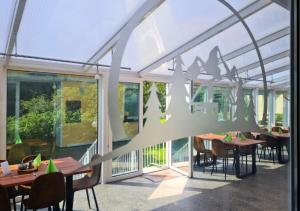 a dining room with tables and chairs and windows at Hotel Garni Harzresidenz in Thale