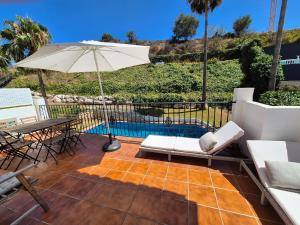 a patio with a table and an umbrella and a pool at Luxury home by the beach in Benalmádena