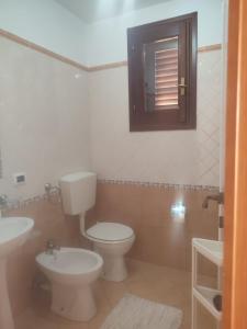 a bathroom with a toilet and a sink and a window at Appartamenti Za Barbara in Lampedusa +10 photos