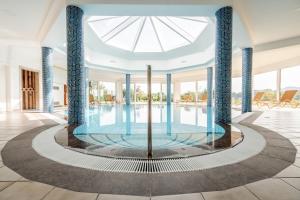 duży basen z niebieskimi kolumnami w budynku w obiekcie Hotel Römerstein w mieście Loipersdorf bei Fürstenfeld