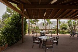 a patio with tables and chairs and palm trees at Agriturismo Bellajo - Ville Rustiche con Piscina in Agrigento