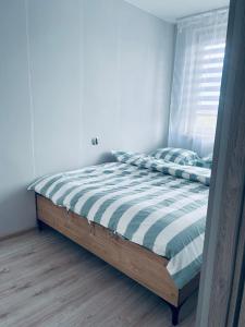 ein Schlafzimmer mit einem Bett mit gestreifter Decke und einem Fenster in der Unterkunft Apartament Ruciane-Nida in Ruciane-Nida