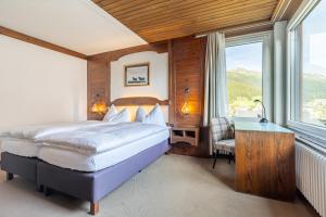 una camera da letto con un letto, una scrivania e una finestra di Hotel Dischma a Davos