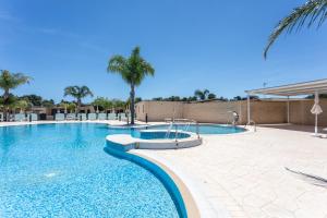 a swimming pool in a resort with palm trees at La Pineta Residence in Otranto