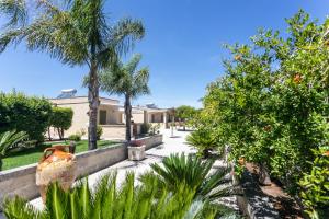a house with a garden with palm trees and plants at La Pineta Residence in Otranto