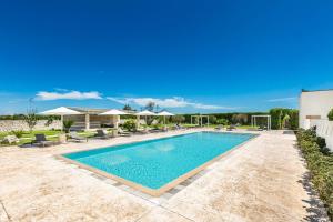 a swimming pool in a yard with chairs and umbrellas at Agriresort Masseria Giovanni in Martano
