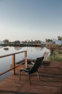 a chair and a table on a dock next to a lake at Moncastro Glamping in Vylkove