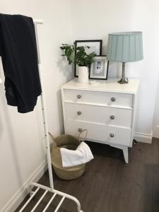 a bedroom with a dresser and a lamp and a chair at Amazing Cambridge house in Chesterton