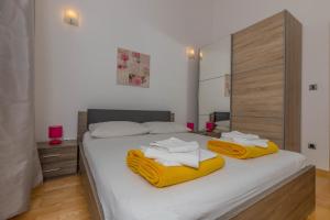 a bedroom with a bed with two towels on it at Polina Apartmani in Klenovica