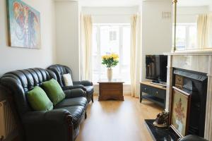 a living room with a leather couch and a television at ChurchMews a Lovely 3 Bedroom Home with Golf, Fishing and Seaside in Donegal
