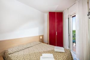 a bedroom with a bed and a red cabinet at Appartamenti BIANCO NERO in Lignano Sabbiadoro