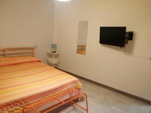 a bedroom with a bed and a tv on the wall at Domus Case Vacanze civico del mare in Castellammare del Golfo