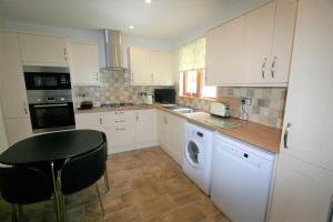 een keuken met witte kasten, een tafel en een vaatwasser bij Loch View Holiday Home, Fort William in Fort William