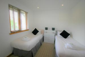 twee bedden in een kamer met witte muren en ramen bij Loch View Holiday Home, Fort William in Fort William