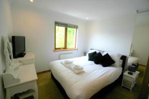 een slaapkamer met een bed met witte lakens en zwarte kussens bij Loch View Holiday Home, Fort William in Fort William