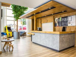 an office lobby with a reception counter and tables at ibis budget Paris Porte de Montreuil in Montreuil