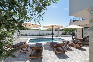 a swimming pool with lounge chairs and umbrellas at CROWONDER Villa Bura with Heated Swimming Pool and Jacuzzi in Privlaka