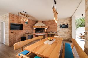 a kitchen with a wooden table and a brick wall at CROWONDER Villa Bura with Heated Swimming Pool and Jacuzzi in Privlaka