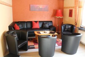 una sala de estar con un sofá de cuero negro y sillas en Ferienhaus am Bach, en Oberdiebach 6 fotos más