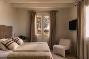 a bedroom with a bed and a chair and a window at Hotel Rural Sant Ignasi in Ciutadella