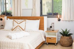 a bedroom with a white bed with a wooden headboard at פרדייז ברמה in Had Nes +65 photos