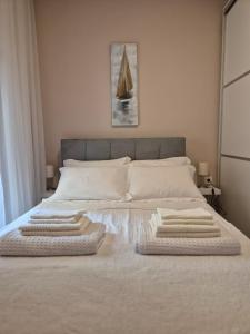 1 cama blanca grande con 3 toallas. en Galeriya Apartment, en Tesalónica